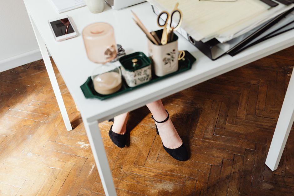 A beautiful minimalist desk setup with stationery and elegant shoes visible underneath.