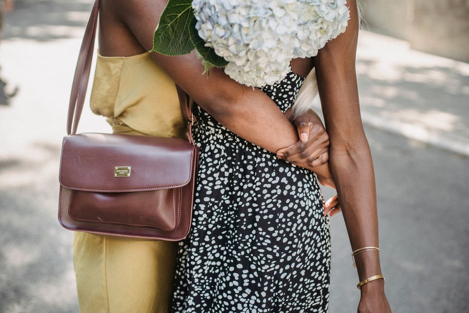 Close-up of two women embracing with a bouquet of hydrangeas outdoors, showcasing friendship and unity.
