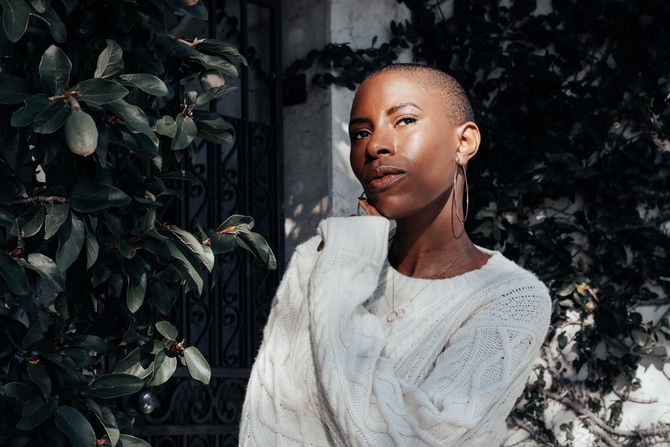Chic outdoor portrait of a young woman posing in sunlight, exuding confidence and style.
