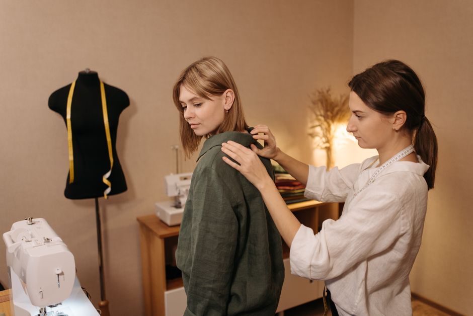 Tailor fitting a woman's dress with precision in a cozy studio setting.