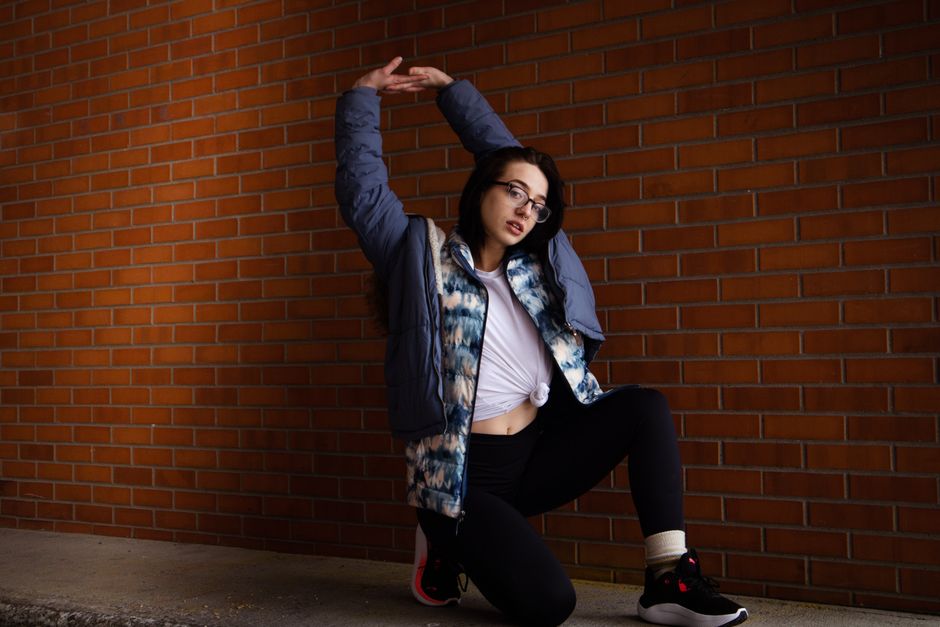 Stylish woman poses confidently against a brick wall, showcasing modern casual fashion.