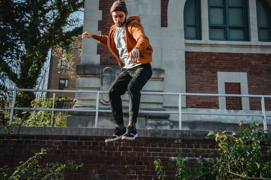 From below full body of active male jumping above ground with hands outstretched during parkour practice