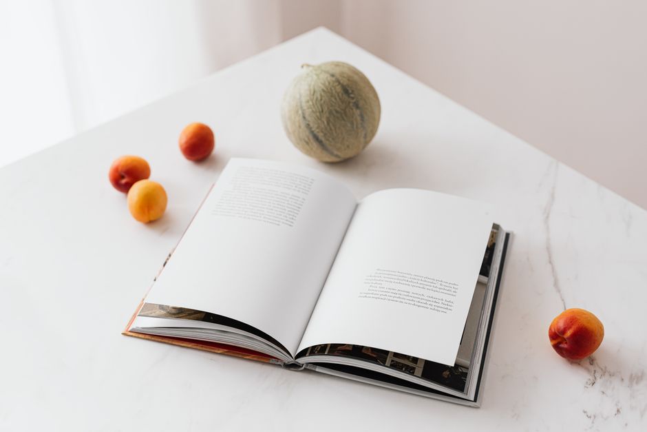 High angle of opened book on marble table composed with colorful ripe apricots and melon