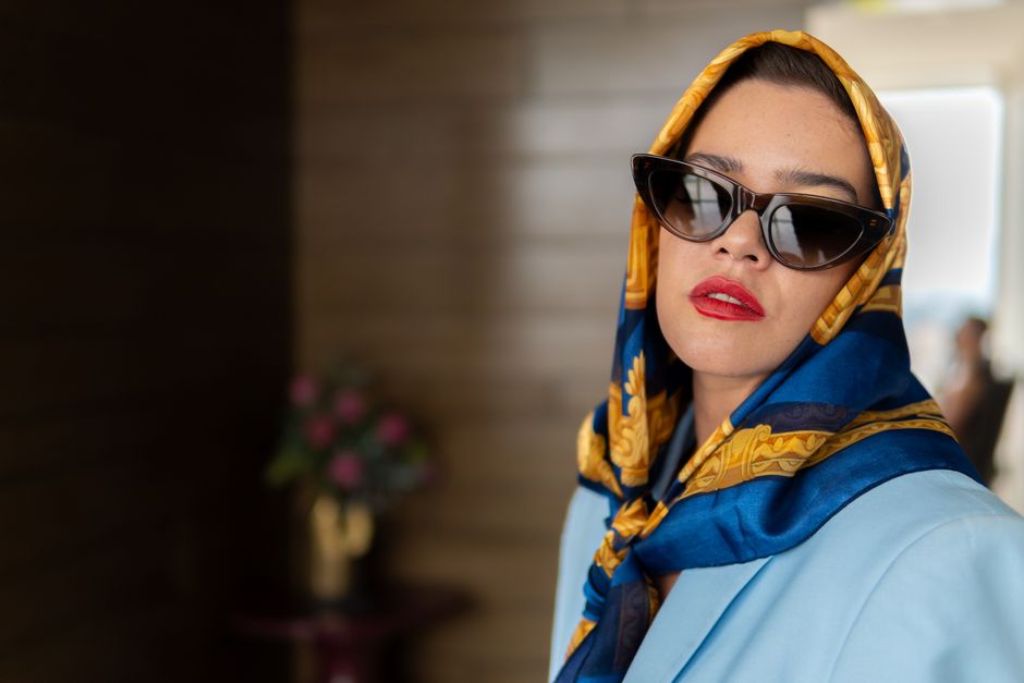 Elegant woman in blue outfit and scarf, wearing black sunglasses indoors, Mexico City.