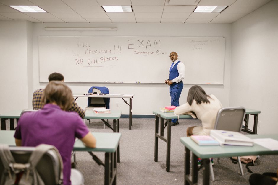 A college educator proctoring an exam, enforcing no cheating rules.