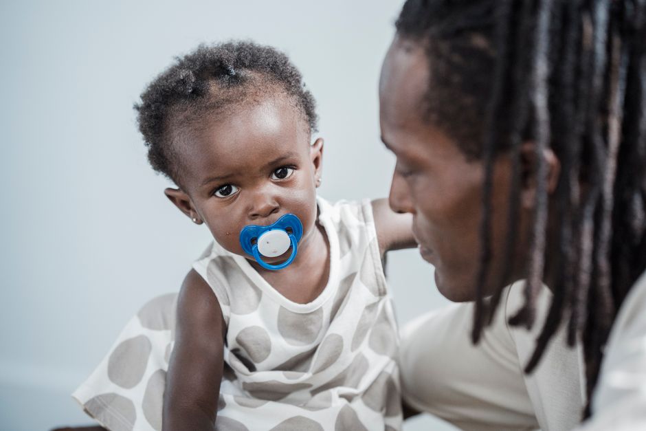 Father shares a tender moment with his baby daughter, who is holding a pacifier.