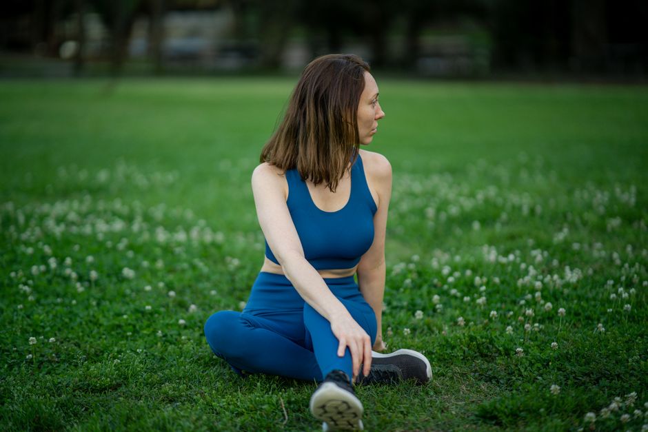 Woman practicing yoga outdoors in a serene green park setting.