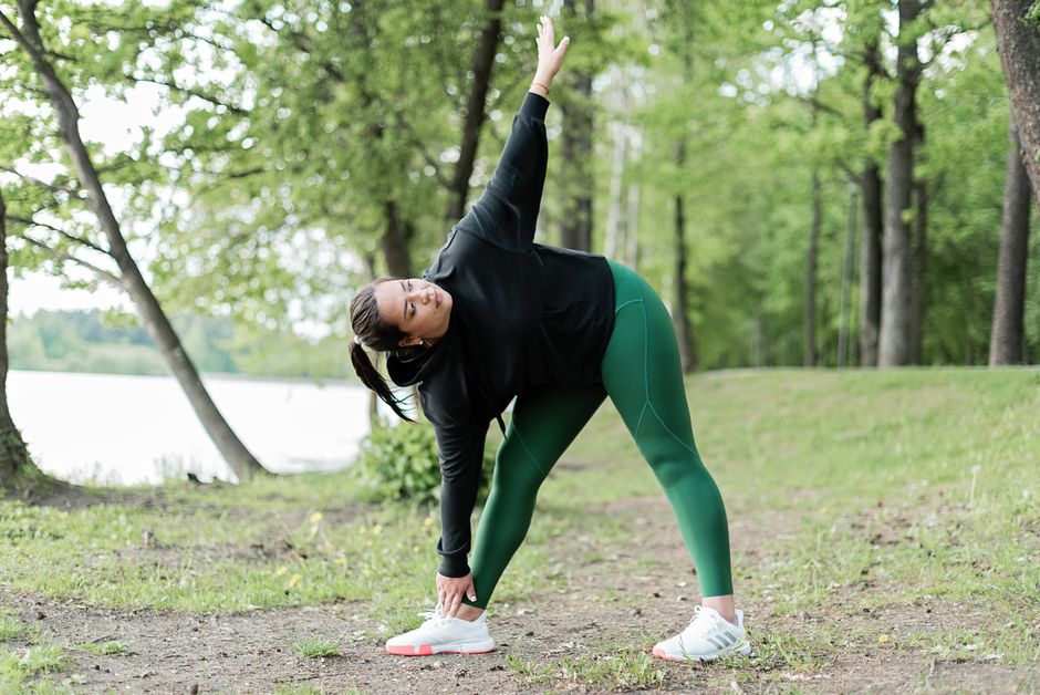 A woman stretches in an outdoor park, promoting a healthy lifestyle.