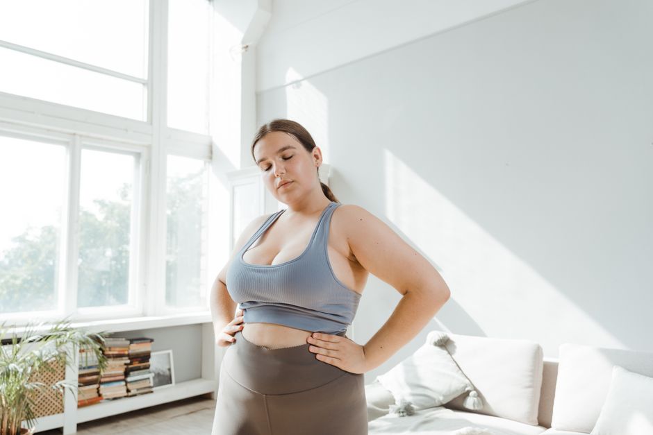 Plus-size woman in sportswear embracing body positivity indoors.