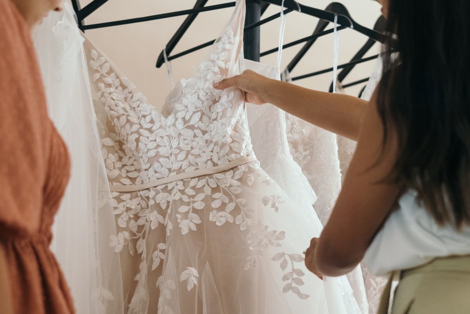 Beautiful lacy wedding dresses being examined in a boutique setting.