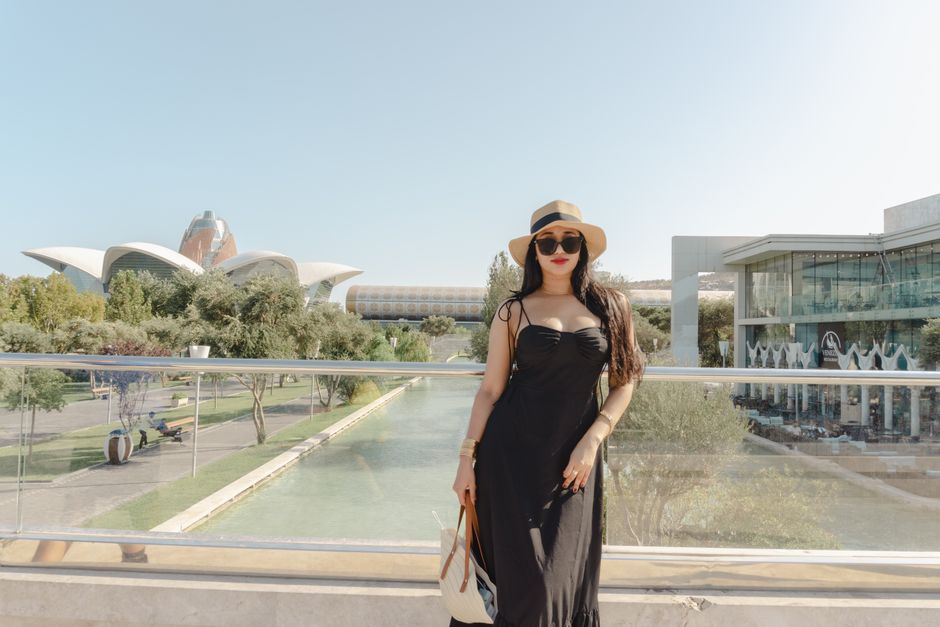 Young woman in trendy summer outfit enjoys a sunny day at Baku's iconic landmarks.