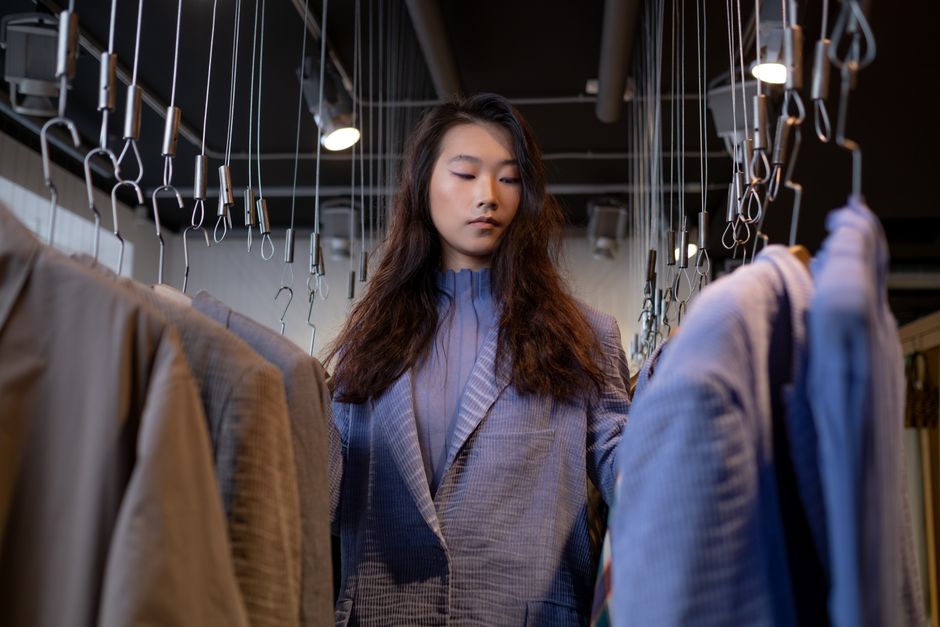 A stylish young woman browsing clothing options in a chic boutique.