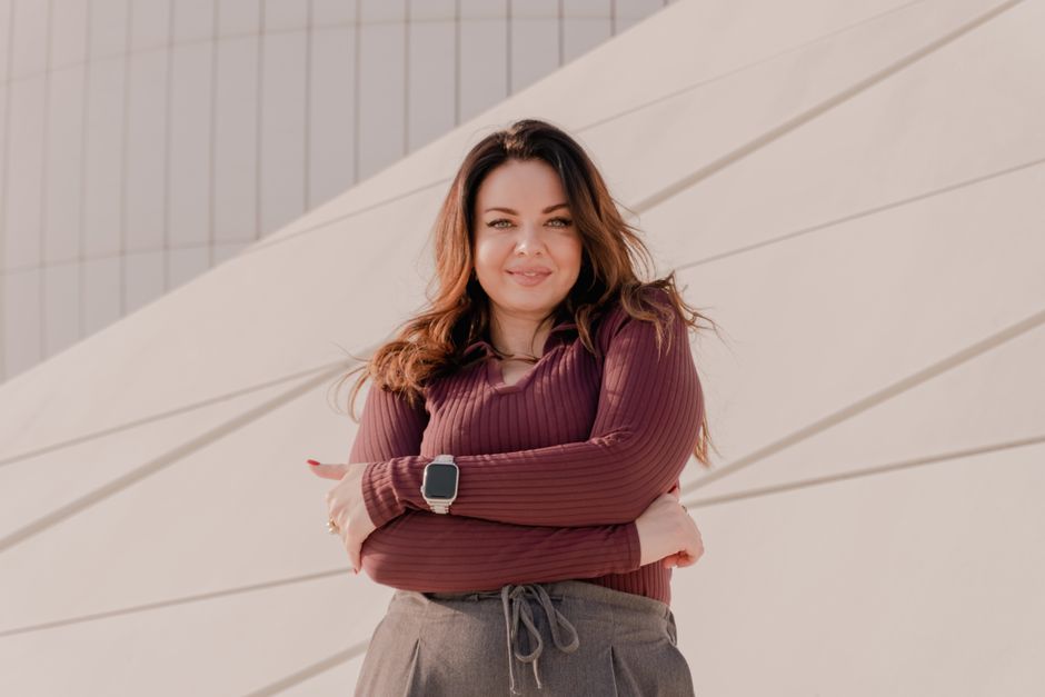 Portrait of a confident woman posing in front of contemporary architectural structure.