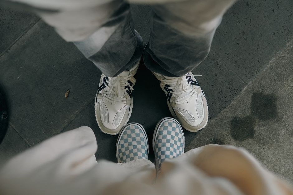 Top-down view of two pairs of casual shoes on pavement, showcasing different footwear styles.