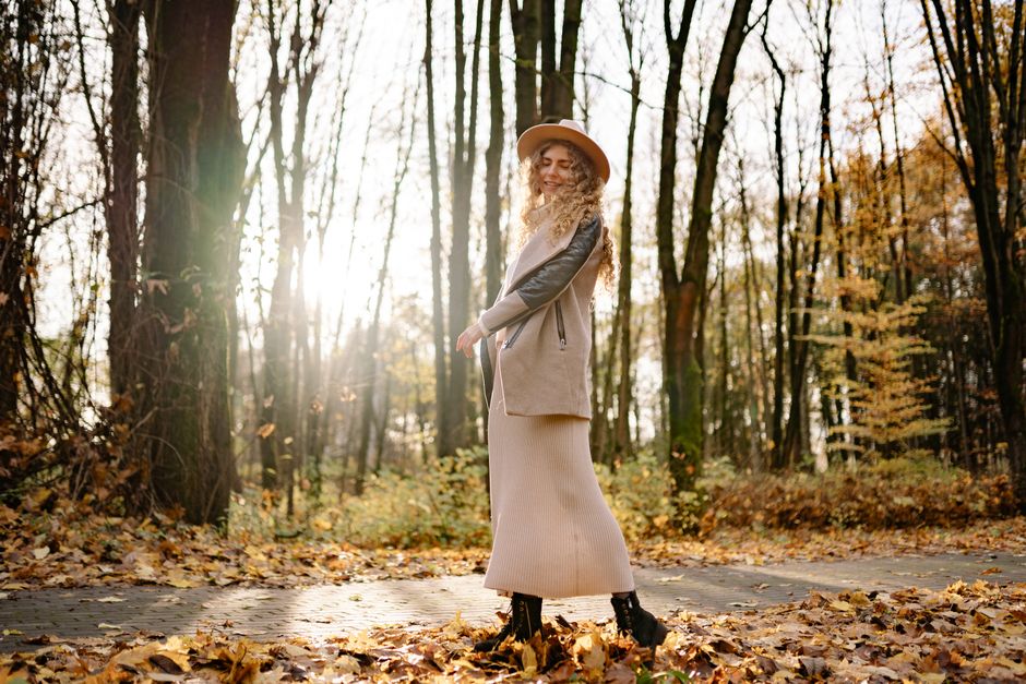 Woman enjoying a sunny autumn day walking through a forest of fallen leaves.